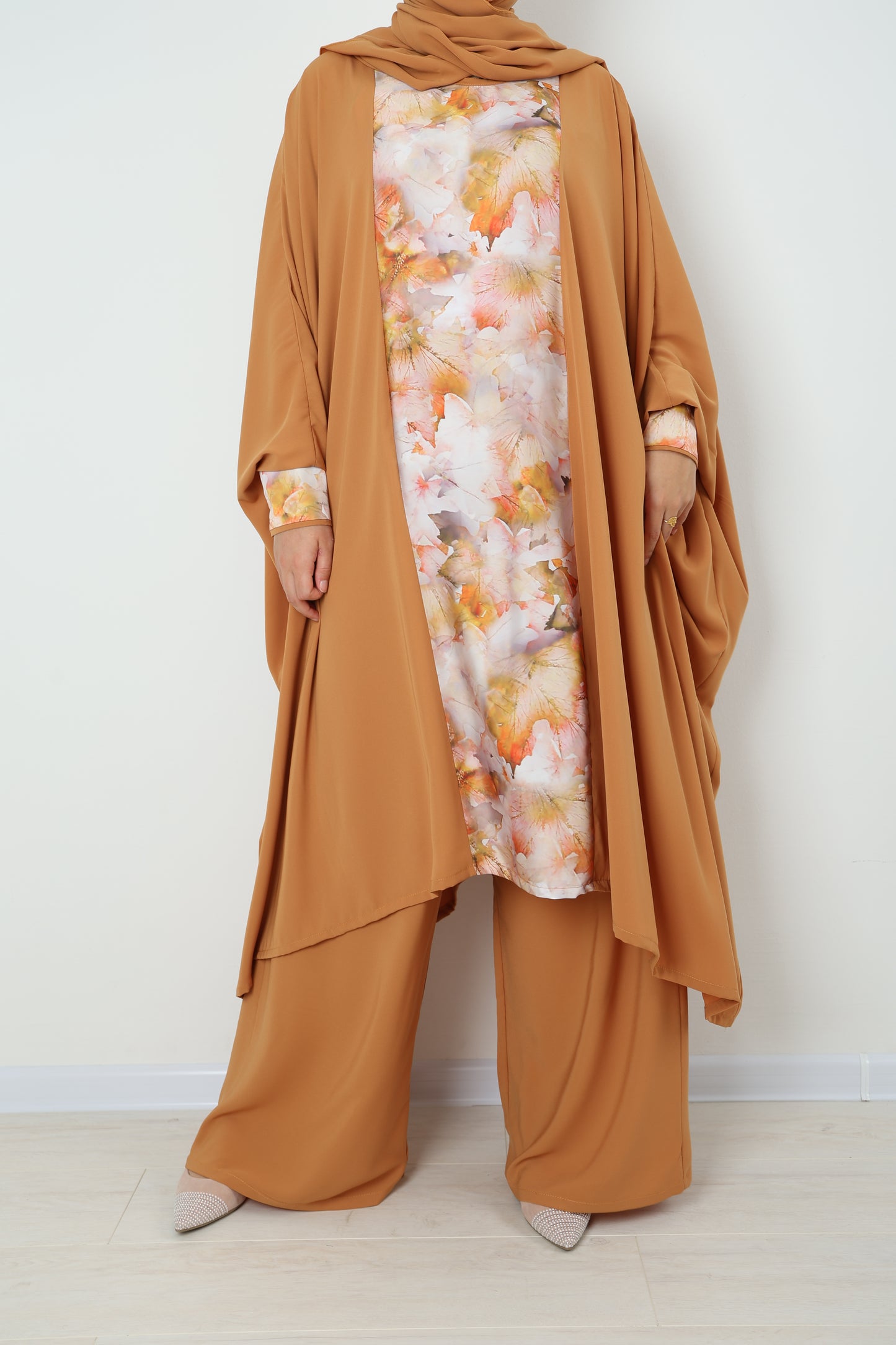 Person wearing a brown outfit with a floral patterned inner lining on a white background